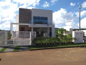 a white house with a fence in front of it at Casa alto padrão Capitólio Lago Vitória in Capitólio