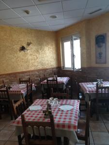 un restaurant avec des tables, des chaises et des nappes rouges et blanches dans l'établissement Hostal San Pedro, à Coslada