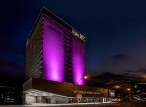Avani Windhoek Hotel & Casino في ويندهوك: فندق اضاءه ارجوانيه من جهه