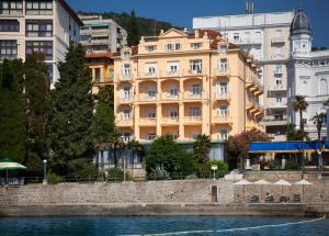 un gran edificio amarillo junto a un río con edificios en Hotel Lungomare Opatija - Liburnia en Opatija
