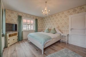 a bedroom with a bed and a television and a chandelier at Ferienhaus Christina in Reichensachsen
