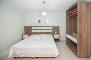 1 dormitorio con 1 cama blanca grande y armarios de madera en Hotel Castelo en Gravatal