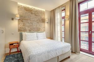 a bedroom with a white bed and a stone wall at Oporto Home Wine Cellars in Vila Nova de Gaia