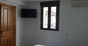 a room with a window and a television on a wall at Pensión STOP in El Cubillo de Uceda