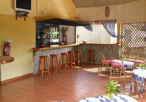 a bar with wooden stools in a restaurant at Le Petit Quartier "Chez Amanthia" in Cap Skirring