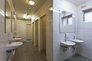 un bagno con quattro lavandini e una fila di specchi di City Centre Budget Hotel a Melbourne