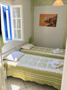 two beds sitting in a room with a window at Pension Sofia Amorgos-Katapola in Katapola