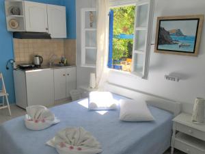 a room with a bed and a kitchen with a window at Pension Sofia Amorgos-Katapola in Katapola