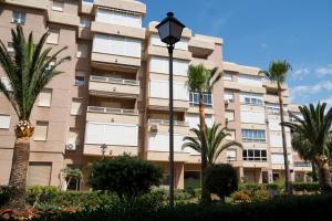 a large building with palm trees in front of it at Apartamento Punta de Torrox in Torrox