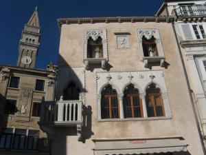 a building with a clock tower in the background at Benecanka Casa Veneziana Piran in Piran