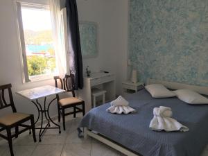 a bedroom with a bed and a table and a window at Pension Sofia Amorgos-Katapola in Katapola