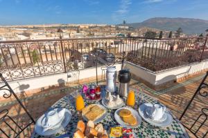 a table with breakfast food on a balcony with a view at Le Grand Alcazar - Riad in Fez