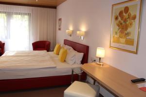a hotel room with a bed and a desk with a lamp at Hotel Rebstock in Ohlsbach