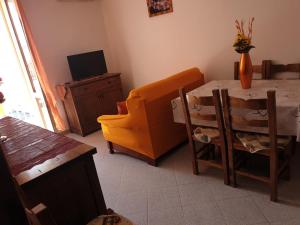 uma sala de estar com uma mesa e uma cadeira e uma televisão em Pretty Appartament Beb em Alghero