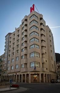 un grand bâtiment avec un haut rouge en haut dans l'établissement Aparthotel Arenteiro, à Carballino