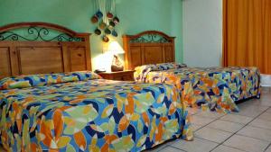 a hotel room with two beds with colorful sheets at Hotel Hacienda Bugambilias in La Paz