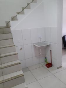 Un baño blanco con lavabo y escaleras. en Arraial do Cabo - Praia do Pontal, en Arraial do Cabo