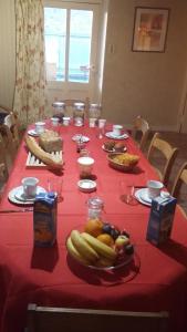 a long table with a red table cloth with fruit on it at La Source in Saint-Amand-Magnazeix