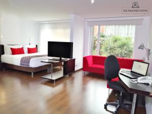 a hotel room with a bed and a red couch at Richmond Suites Hotel in Bogotá