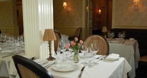 a table with glasses and a vase of flowers on it at The Hewitt Wellington Hotel in Spring Lake