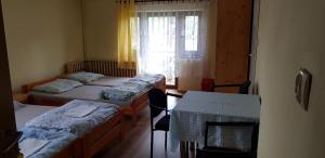 ズバルドンにあるChata u Żabyのベッド3台、テーブル、窓が備わる客室です。