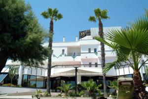 ein Gebäude mit Palmen davor in der Unterkunft Hyencos Hotel Calos in Torre San Giovanni Ugento