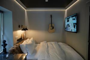 ein Schlafzimmer mit einem Bett und einer Gitarre an der Wand in der Unterkunft Hotel Akureyri Dynheimar in Akureyri
