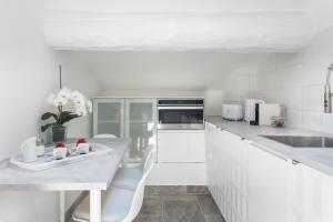 a white kitchen with a table and white appliances at My Pad Provence 5 in Avignon