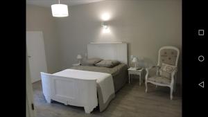 1 dormitorio con 1 cama blanca y 1 silla en GITE IZALIN AVEC SPA A 20 min du Puy du Fou, en Mauléon