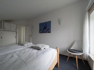 a white bedroom with a bed and a chair at Ferienwohnung-Himmelblau-auf-dem-Ferien-Bauernhof-Nielson-in-Bisdorf-in-Inselmitte in Bisdorf