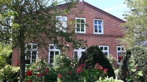 une maison en briques rouges avec des fleurs devant elle dans l'établissement Ferienwohnung-Rosenrot-auf-dem-Ferien-Bauernhof-Nilson-in-Inselmitte, à Bisdorf