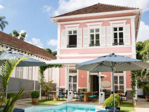 une maison rose avec une piscine et deux parasols dans l'établissement Casa Rosa Hotel Boutique, à Petrópolis