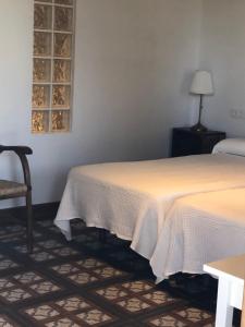two beds in a room with a table and a chair at Alojamiento Rural El Soldao in Medina Sidonia