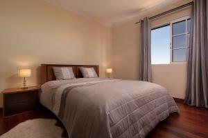 une chambre avec un grand lit et une grande fenêtre dans l'établissement Villa Neto, à Calheta