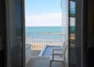 un balcón con vistas a la playa y una silla en Hotel Alexander Museum Palace en Pesaro