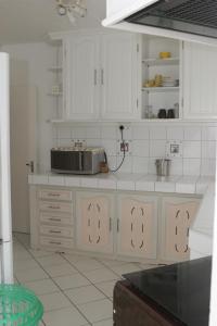a kitchen with white cabinets and a microwave on a counter at Le Grand Cacatoie in Blue Bay