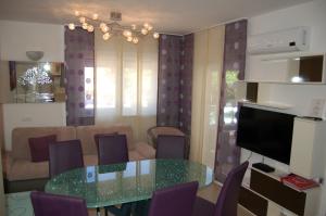 uma sala de estar com uma mesa de vidro e cadeiras roxas em Apartmani FAMILY em Sveti Filip i Jakov