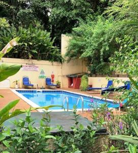 - une piscine dans une cour avec des chaises et des arbres dans l'établissement Résidence Bertille Abidjan Cocody, à Abidjan
