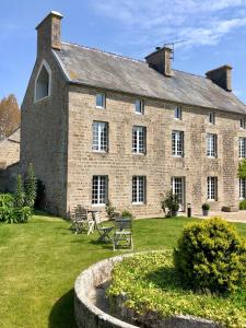 a large brick building with chairs in a yard at La Maison Gervaiserie & Spa in Réville