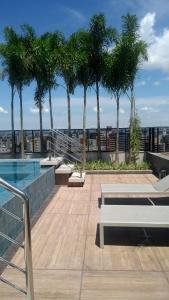 a swimming pool on top of a building with palm trees at Apartamento de luxo no coração da ponta verde in Maceió