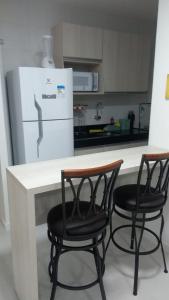 a kitchen with two chairs and a table and a refrigerator at Apartamento de luxo no coração da ponta verde in Maceió