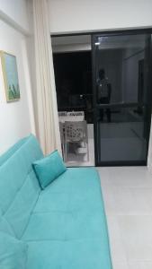a living room with a blue couch and a balcony at Apartamento de luxo no coração da ponta verde in Maceió