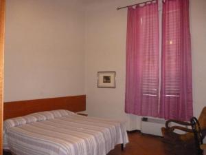 una camera con letto e finestra con tende rosa di 27 Aprile a Firenze