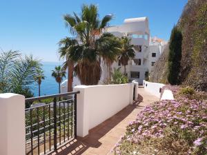 ein weißes Gebäude mit einer Palme und dem Meer in der Unterkunft Apartamento Lujo Calaceite in Torrox Costa