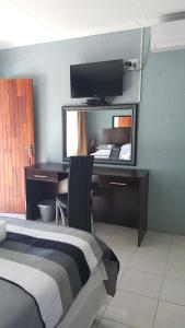 a bedroom with a desk and a bed and a mirror at Silver Rest Guesthouse in Mahikeng