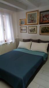 ein blaues Bett in einem Zimmer mit Bildern an der Wand in der Unterkunft Casa Lorella in Chioggia