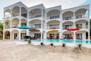 a large building with a swimming pool and umbrellas at Blue Water Beach Villas in San Pedro
