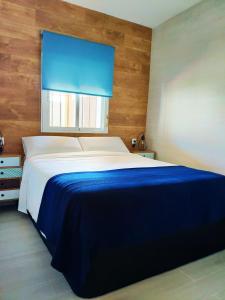 a bedroom with a large bed with a blue blanket at Novoasis in Chiclana de la Frontera
