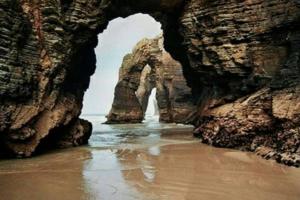 a cave in the ocean with a wave in the water at Foz vacaciones a orillas del mar in Foz