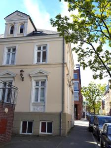 ein weißes Gebäude auf einer Straße mit parkenden Autos in der Unterkunft Apartments Harmsstraße 13 in Kiel